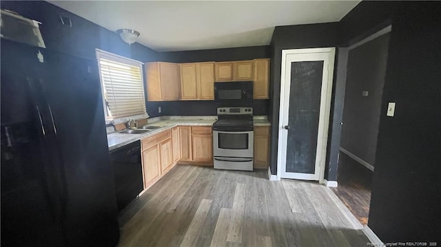 kitchen featuring light brown cabinets, light countertops, a sink, and black appliances