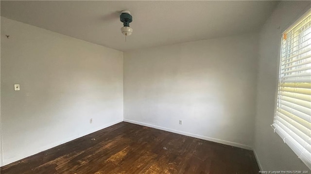 spare room featuring baseboards and dark wood-style floors