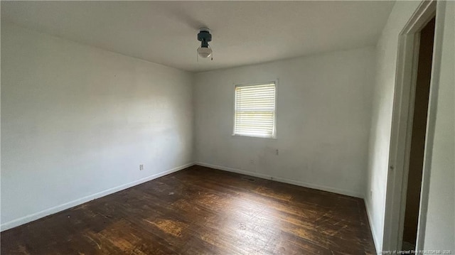 spare room featuring baseboards and dark wood-style flooring