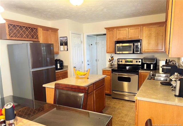 kitchen with a textured ceiling, a kitchen island, and appliances with stainless steel finishes