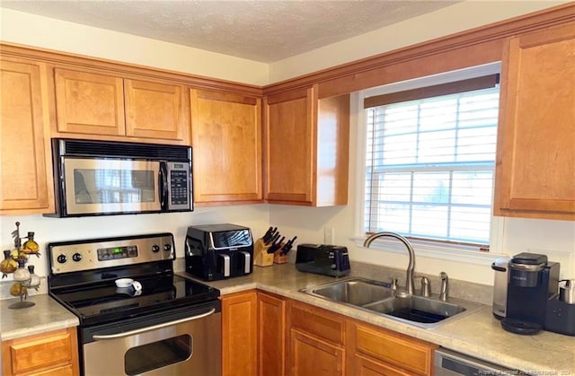 kitchen with a textured ceiling, sink, and appliances with stainless steel finishes