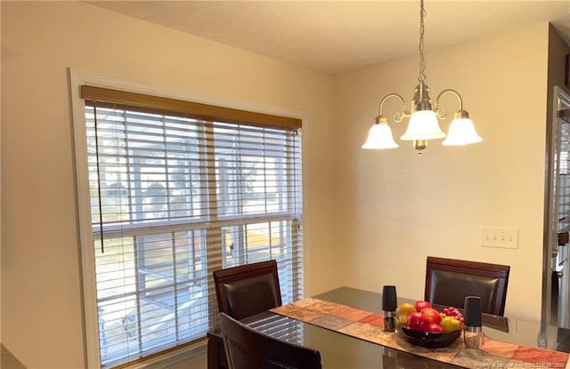 dining area with plenty of natural light, a notable chandelier, and a textured ceiling