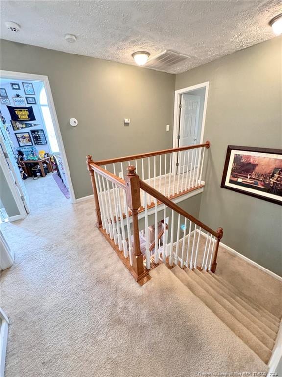 stairway featuring carpet and a textured ceiling