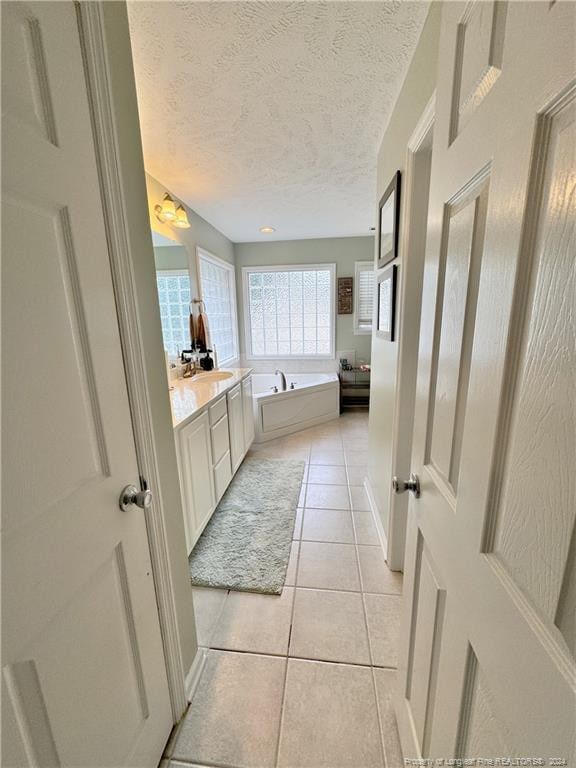 bathroom featuring tile patterned flooring, vanity, a textured ceiling, and a tub