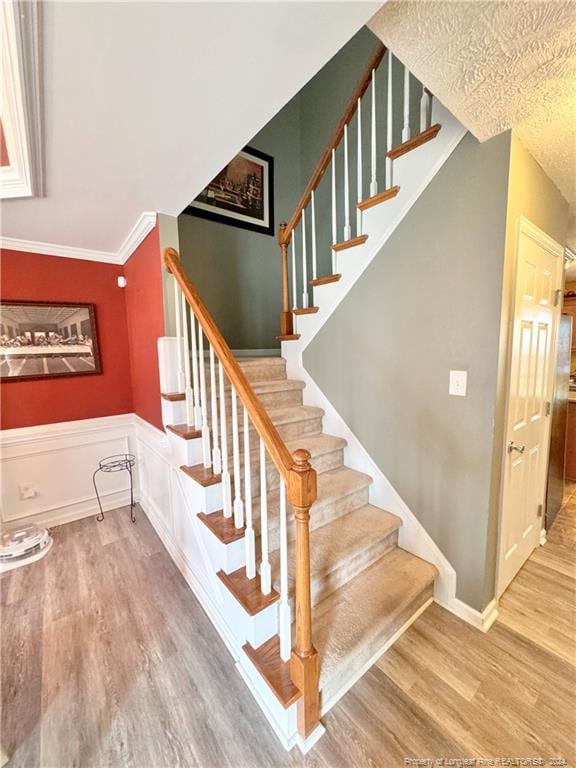 stairway with ornamental molding and hardwood / wood-style floors