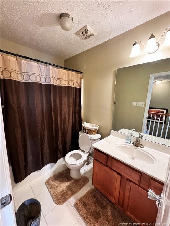 bathroom featuring toilet, vanity, a textured ceiling, and tile patterned flooring