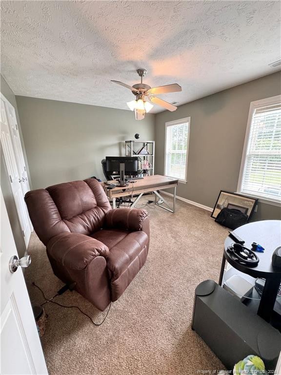 carpeted living room featuring ceiling fan and a textured ceiling