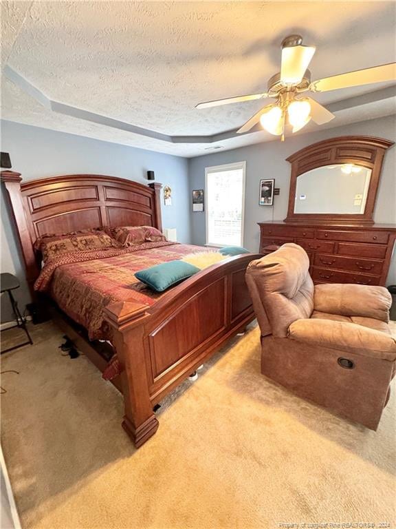 bedroom featuring light colored carpet, a textured ceiling, and ceiling fan