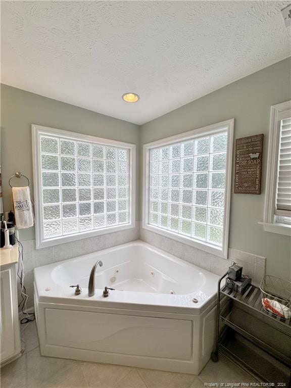 bathroom with a bathtub, a textured ceiling, and tile patterned floors