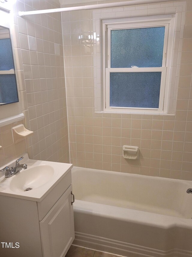 bathroom with tile patterned flooring, tiled shower / bath, and vanity