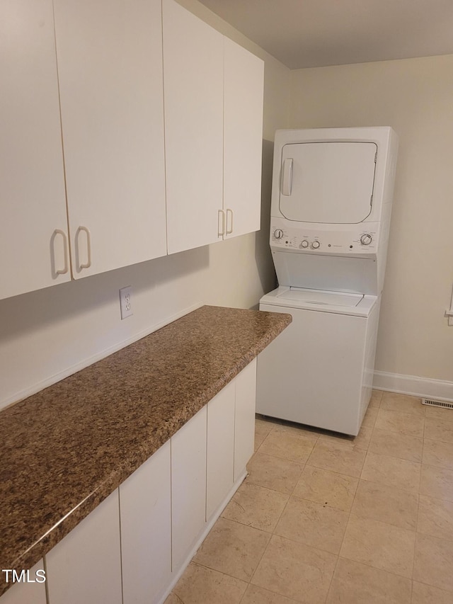 washroom featuring cabinets and stacked washing maching and dryer