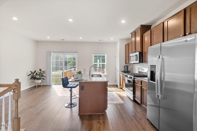 kitchen with a center island with sink, stainless steel appliances, dark hardwood / wood-style floors, and sink