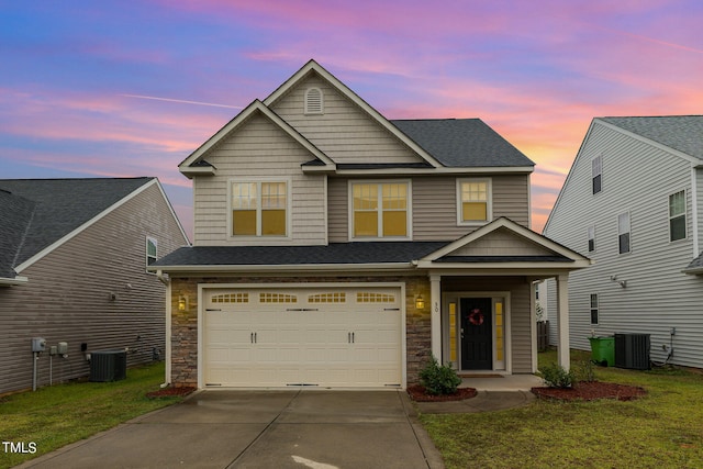 craftsman-style house featuring a lawn, a garage, and central AC unit