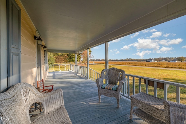 deck with covered porch, a yard, and a rural view