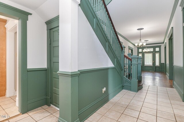 corridor with an inviting chandelier, light wood-type flooring, and crown molding