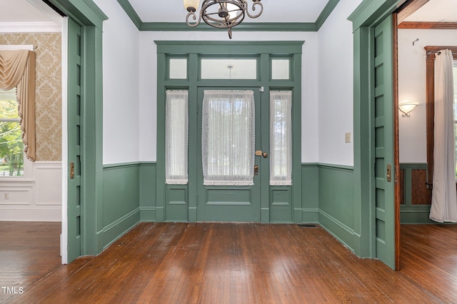 entrance foyer featuring ornamental molding, a chandelier, and dark wood-type flooring