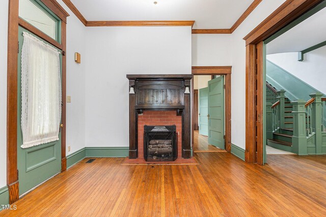 unfurnished living room with wood-type flooring, a fireplace, and ornamental molding