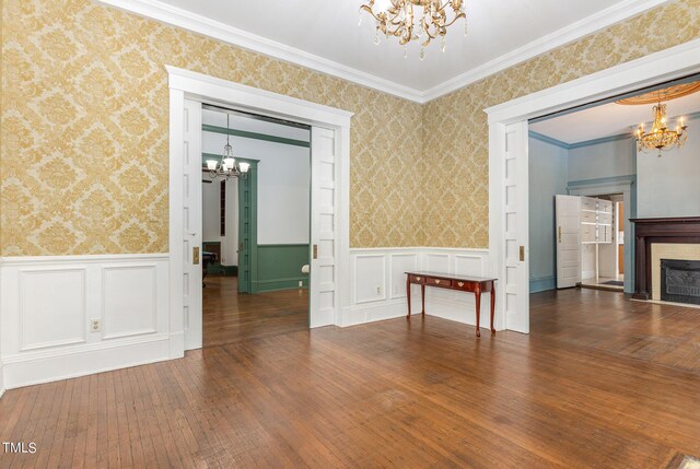 unfurnished room with ornamental molding, a notable chandelier, and dark wood-type flooring