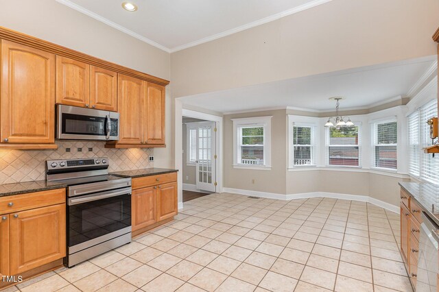 kitchen featuring appliances with stainless steel finishes, light tile patterned floors, crown molding, an inviting chandelier, and dark stone counters