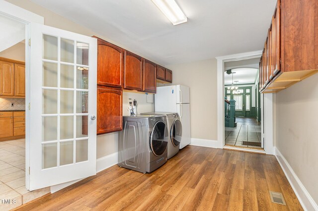 washroom with washer and clothes dryer, cabinets, and light wood-type flooring