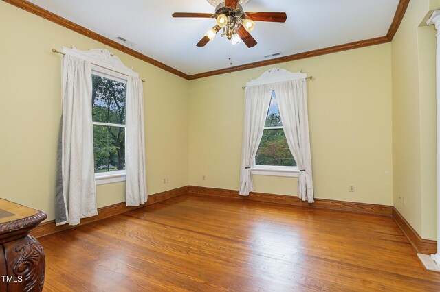 unfurnished room with crown molding, hardwood / wood-style floors, ceiling fan, and plenty of natural light