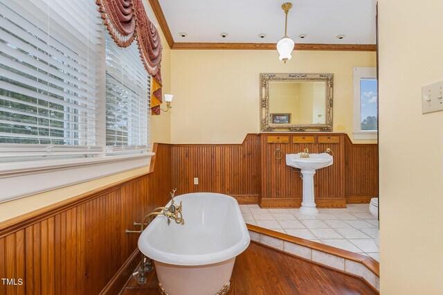 bathroom featuring hardwood / wood-style floors, crown molding, a healthy amount of sunlight, and a bathing tub