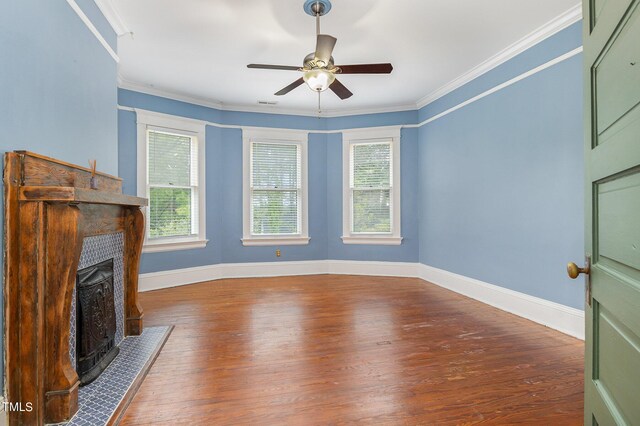 unfurnished living room with a tiled fireplace, ceiling fan, plenty of natural light, and dark wood-type flooring