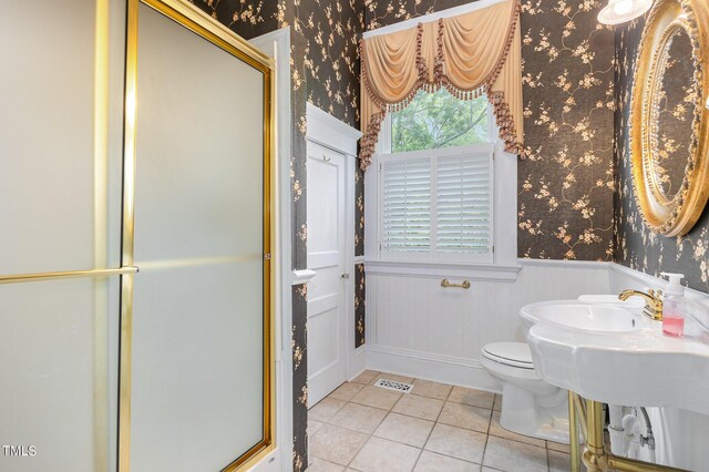 bathroom featuring tile patterned flooring, a shower with door, and toilet