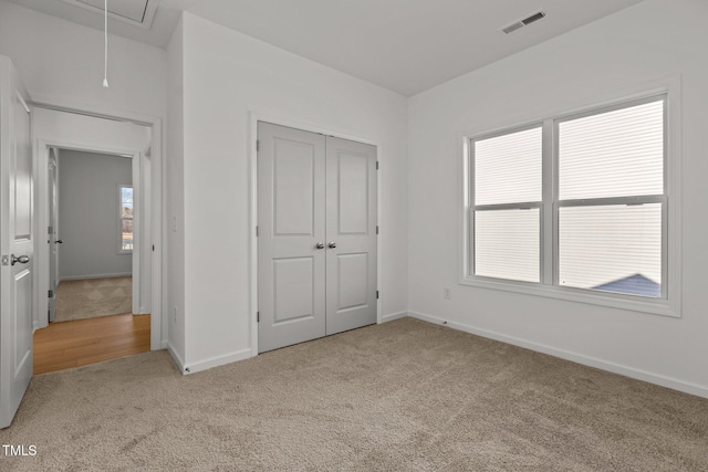 unfurnished bedroom with a closet and light colored carpet