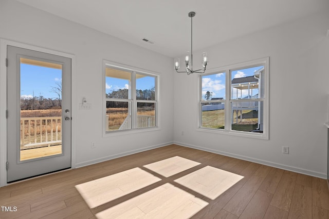 unfurnished dining area with light wood-type flooring and a notable chandelier