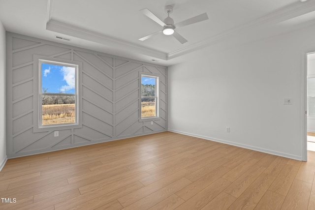 unfurnished room featuring ornamental molding, light hardwood / wood-style floors, and a tray ceiling