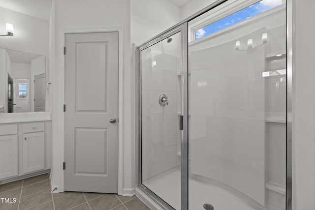 bathroom with tile patterned flooring, a shower with shower door, and vanity