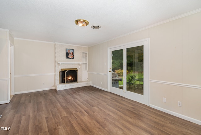 unfurnished living room with a brick fireplace, a textured ceiling, dark hardwood / wood-style floors, and crown molding