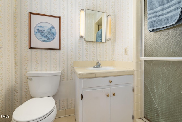 bathroom featuring a shower with shower door, vanity, and toilet