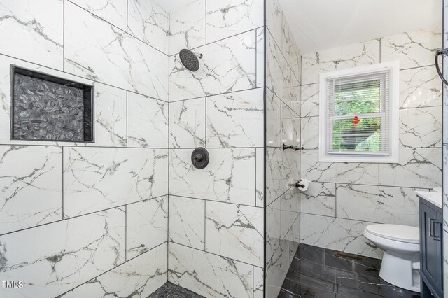 bathroom with toilet, a tile shower, tile walls, and vanity