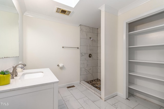 bathroom with a tile shower, vanity, and crown molding