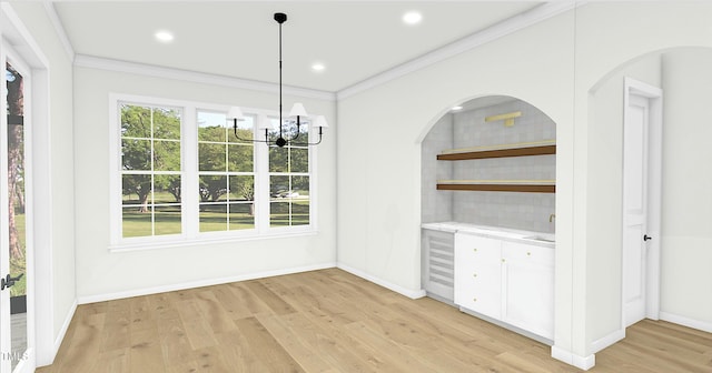 unfurnished dining area featuring ornamental molding, a notable chandelier, and light wood-type flooring