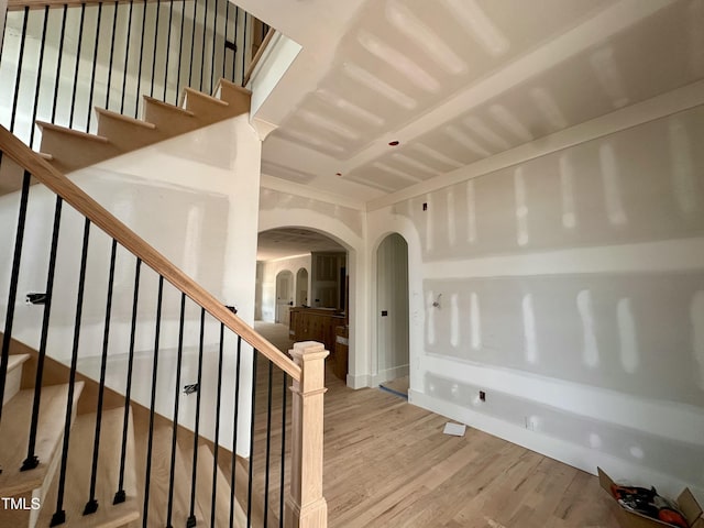 stairway featuring wood finished floors, baseboards, and arched walkways