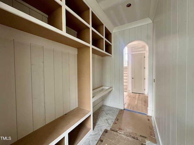 mudroom with arched walkways and wooden walls