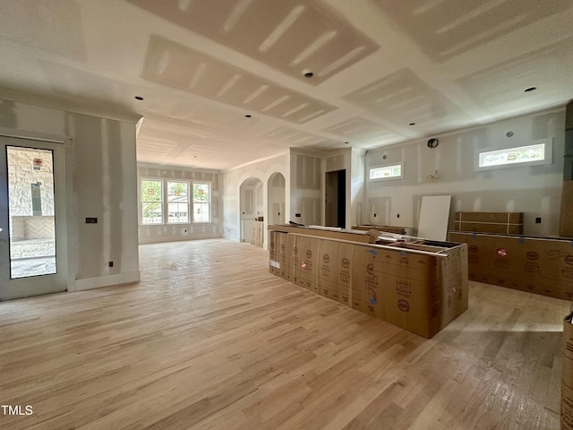 kitchen with arched walkways, open floor plan, light wood-style flooring, and a center island