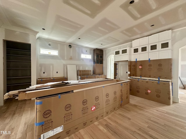 kitchen with light wood-type flooring, glass insert cabinets, and white cabinetry