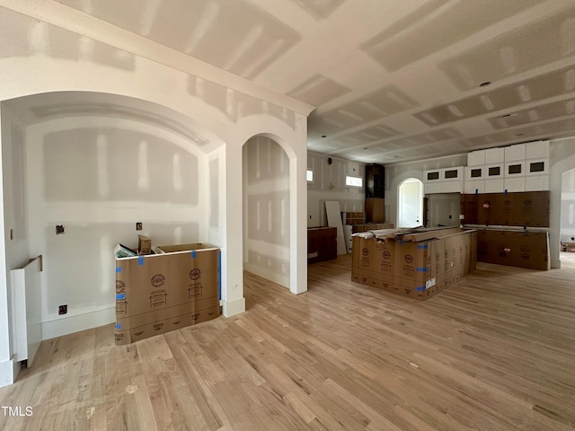 kitchen with glass insert cabinets, baseboards, a spacious island, light wood-style floors, and white cabinets