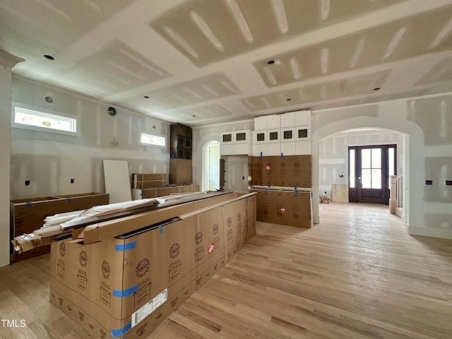 kitchen with light wood-style flooring, glass insert cabinets, a kitchen island, arched walkways, and white cabinets