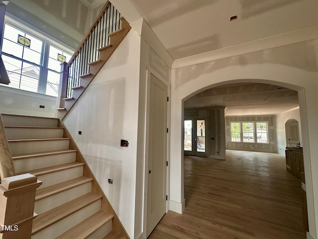 stairs with wood finished floors and arched walkways