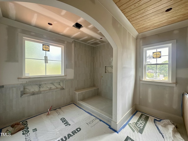 bathroom with a tile shower, baseboards, and wood ceiling