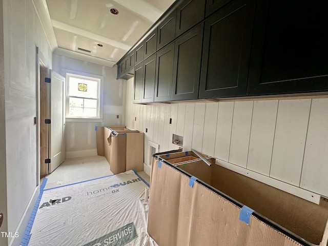 laundry area with electric dryer hookup, cabinet space, and baseboards