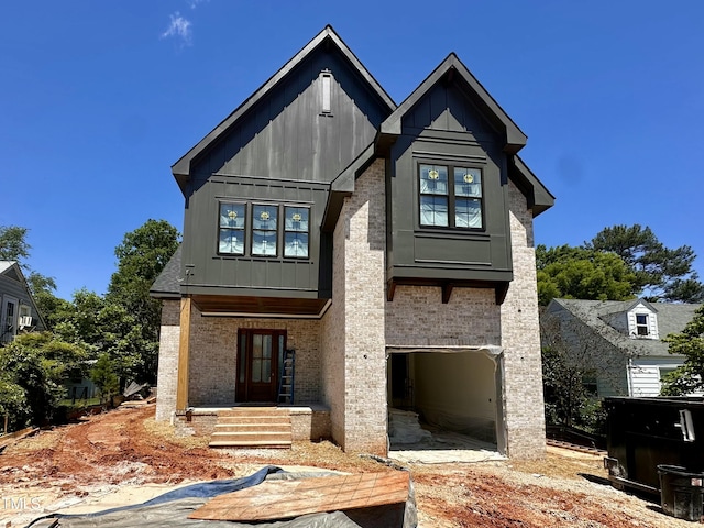 view of front facade with an attached garage, board and batten siding, and brick siding