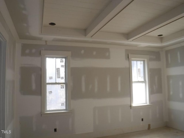 empty room with beam ceiling and a healthy amount of sunlight