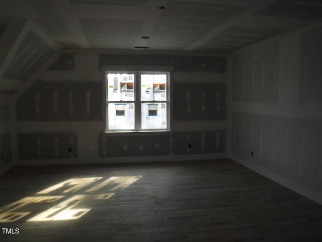 unfurnished room featuring dark wood-type flooring and vaulted ceiling