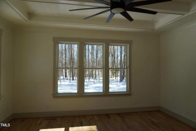 empty room with baseboards, a raised ceiling, and dark wood-style flooring